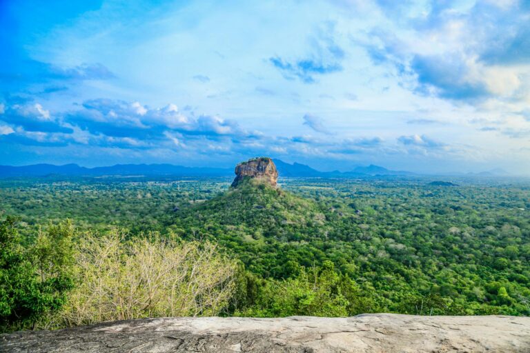 Breathtaking panoramic view of Sigiriya Rock amidst lush greenery in Sri Lanka under a vibrant sky.